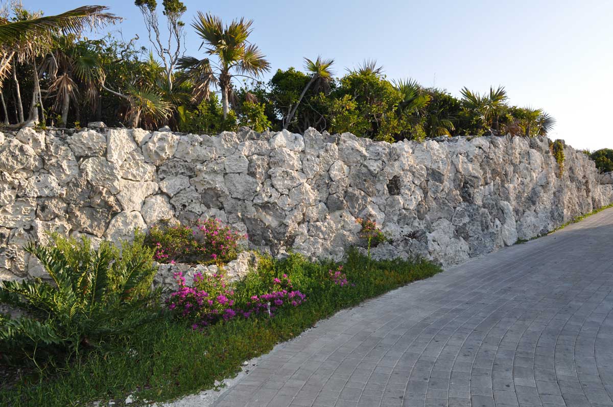 To put the road in, there was a cut into the native limestone. Native rock was collected throughout the island and used as a veneer stone to eliminate the look of cut limestone into the grade. 